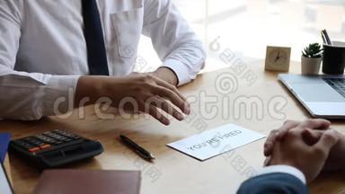 经理坐在办公桌前，给员工发一个解雇信封，指着违反规定的员工的脸